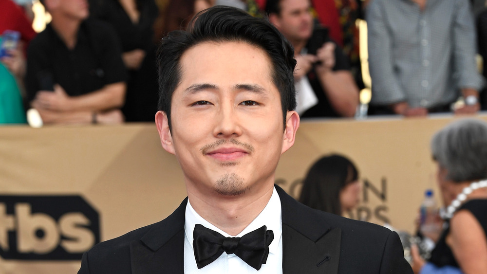 Steven Yeun sorride in smoking 