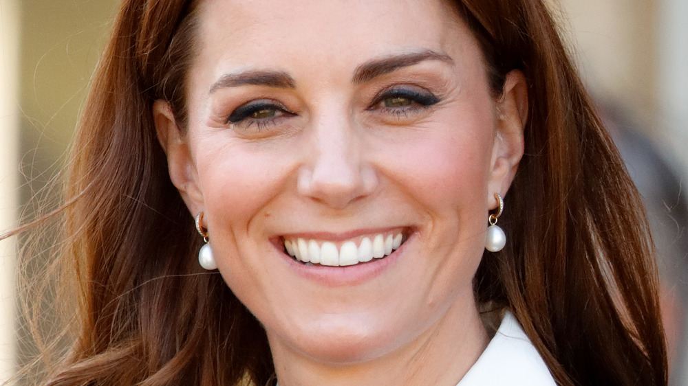 Kate Middleton sorride mentre indossa orecchini di perle