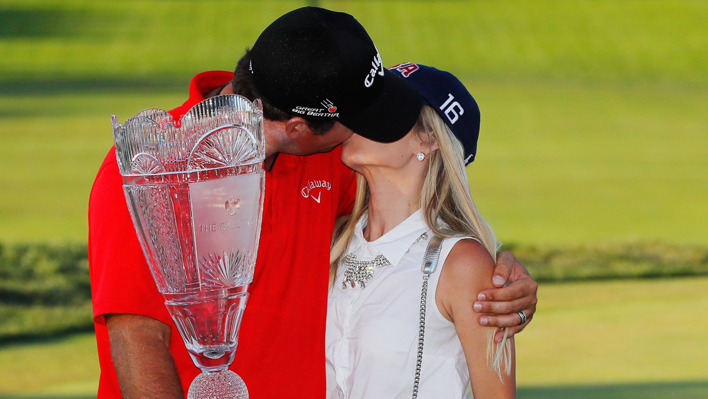 Patrick Reed e Justine Reed si baciano, entrambi indossano cappelli, sul campo da golf, indossano cappelli