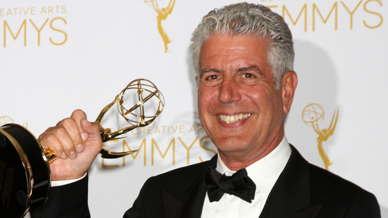 Anthony Bourdain sorride e tiene in mano un Emmy