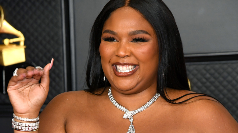 Lizzo sorridendo e salutando 