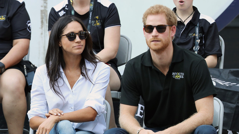 Meghan Markle Il principe Harry è seduto e indossa occhiali da sole 
