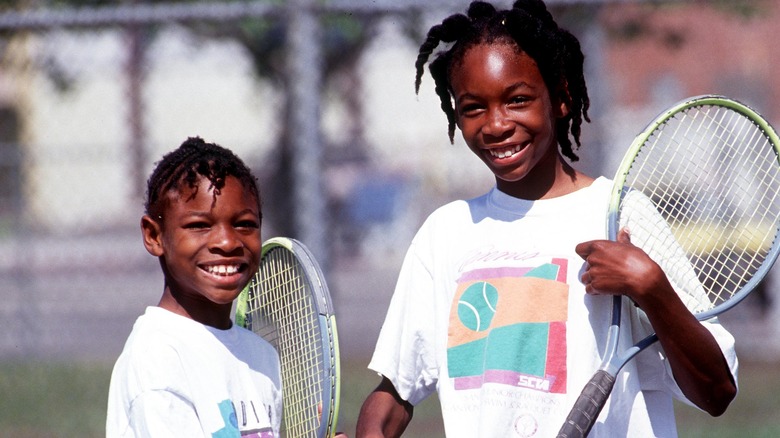 Serena Williams con la sorella maggiore Venus Williams nel 1991, con in mano le racchette su un campo da tennis