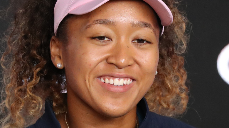 Naomi Osaka sorride e indossa una visiera rosa