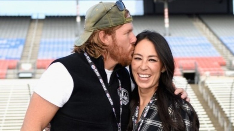 Chip Gaines con un cappello da baseball che bacia la moglie Joanna