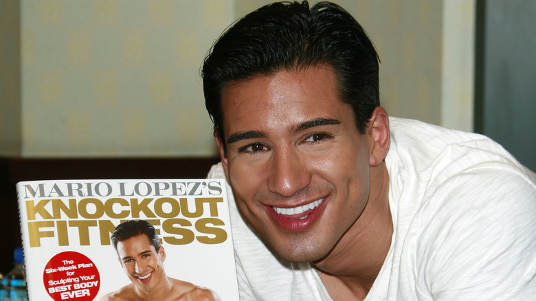 Mario Lopez sorride con il suo libro di fitness