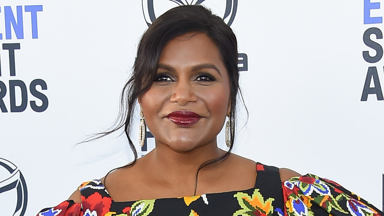 Mindy Kaling sorride, distoglie lo sguardo