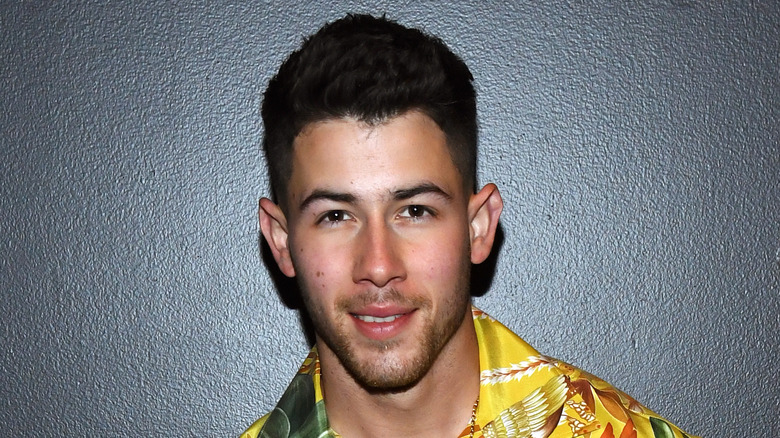 Nick Jonas sorride davanti a sfondo nero