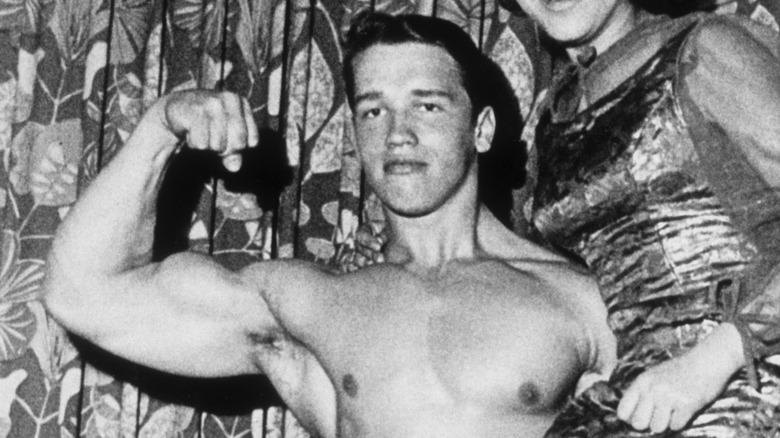 Un giovane Arnold Schwarzenegger si flette