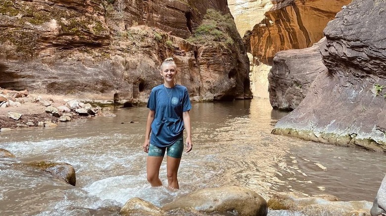 Gabby Petito sorridente, guadando in acqua tra le montagne