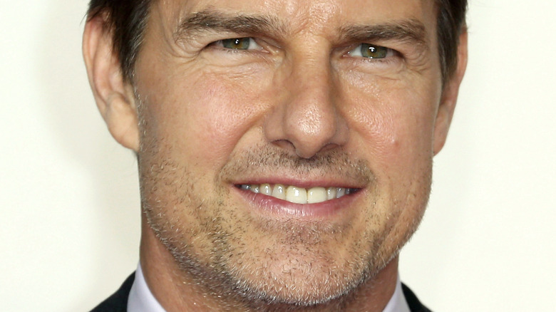 Tom Cruise sorride davanti a uno sfondo bianco