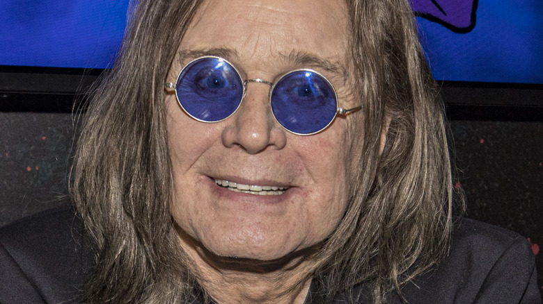 Ozzy Osbourne sorridente con gli occhiali rotondi blu