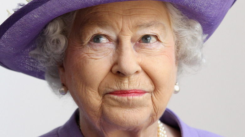 Cappello viola con piccolo sorriso della regina Elisabetta