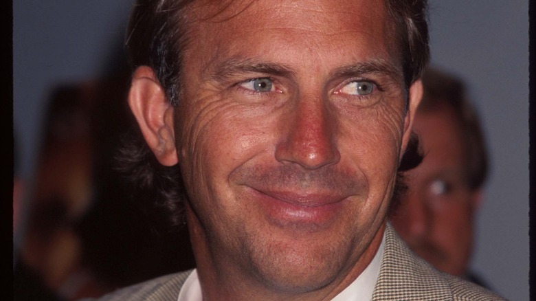Kevin Costner sorride in abito marrone chiaro
