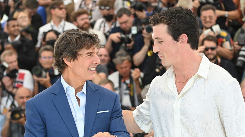 Tom Cruise e Miles Teller sorridono