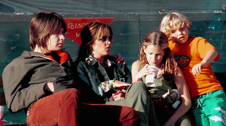 Una giovane Riley Keough con la famiglia, tutti seduti, distogliendo lo sguardo