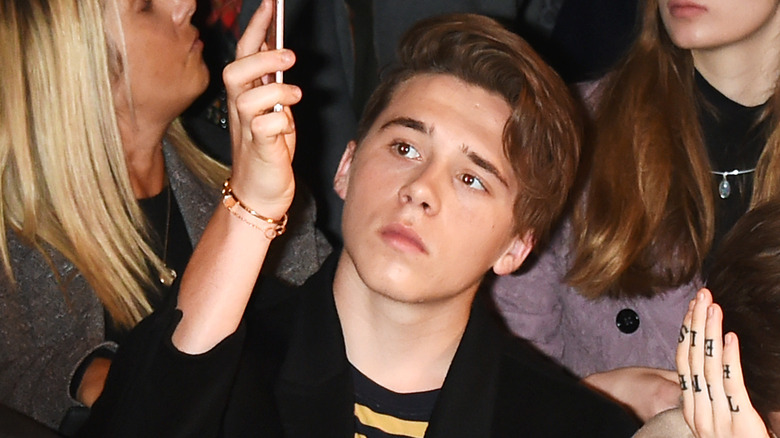 Brooklyn Beckham che guarda il telefono