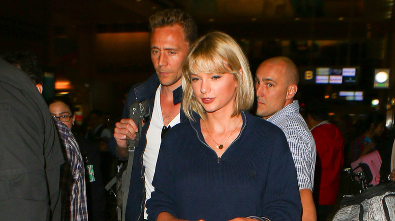 Tom Hiddleston accigliato dietro Taylor Swift