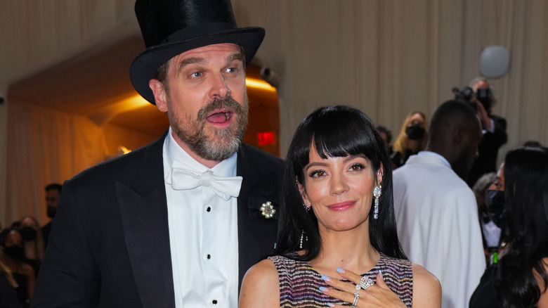 David Harbour indossa un cappello a cilindro, Lily Allen con una mano sul petto