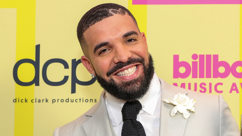 Drake sorridente in giacca e cravatta