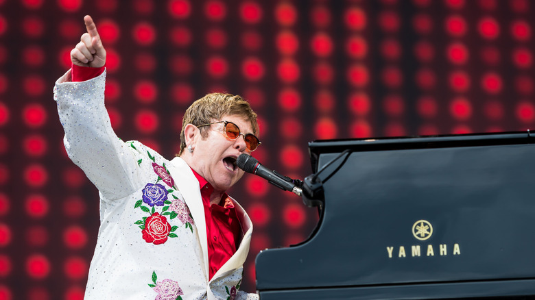 Elton John si esibisce sul palco e indica