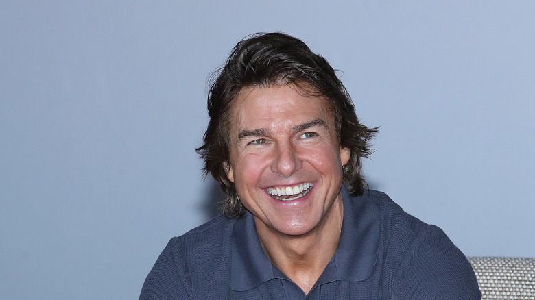 La maglietta blu con colletto di Tom Cruise sorride