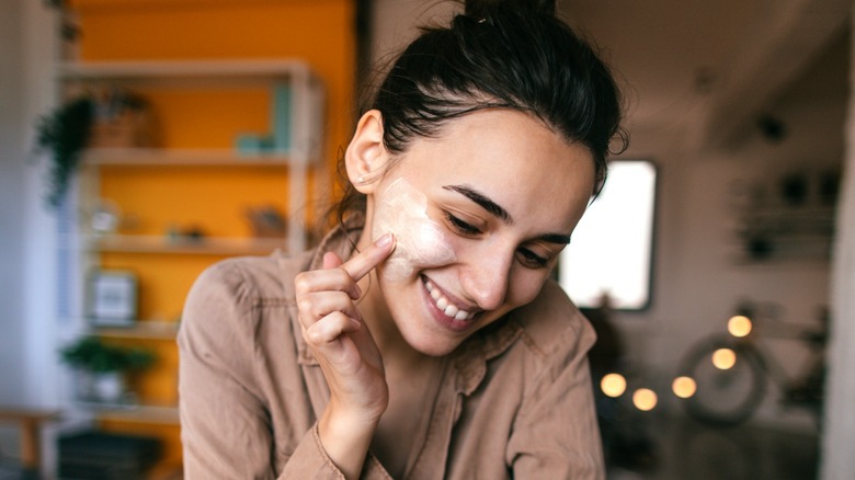 Donna sorridente che applica cosmetici