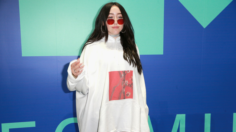 Noah Cyrus con i capelli neri e gli occhiali da sole rossi