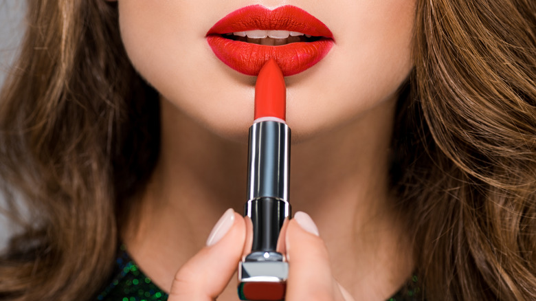 Donna che mette il rossetto rosso