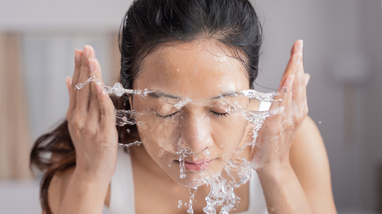 Una donna che si spruzza acqua sul viso