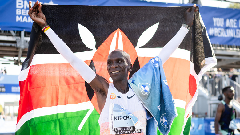 Eliud Kipchoge festeggia la vittoria con la bandiera dietro di lui