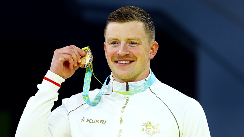 Adam Peaty con in mano una medaglia