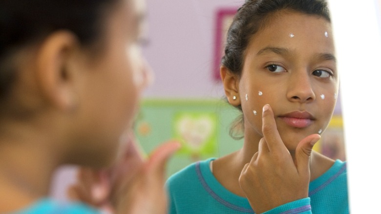 Ragazza che applica la crema per il viso