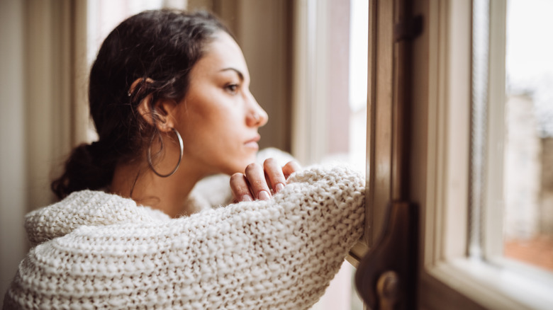 Donna turbata che guarda fuori dalla finestra