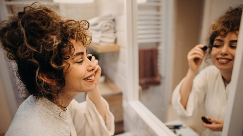 donna che applica il mascara allo specchio