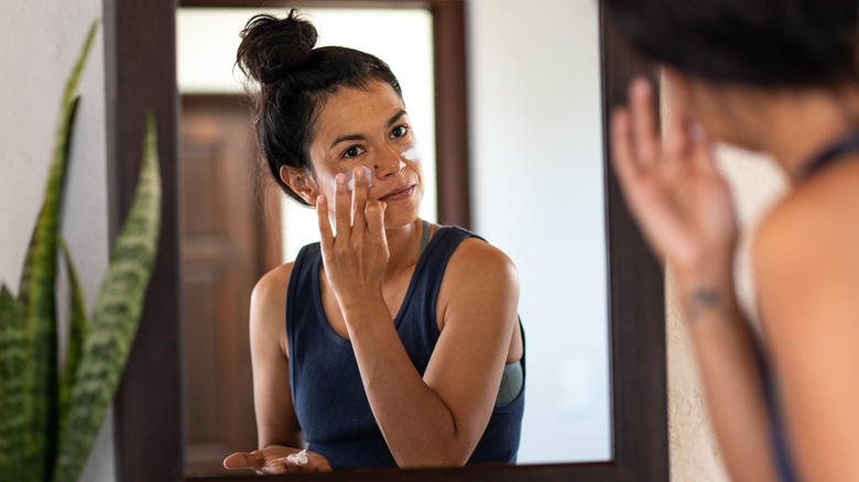 Donna che applica la crema solare sul viso