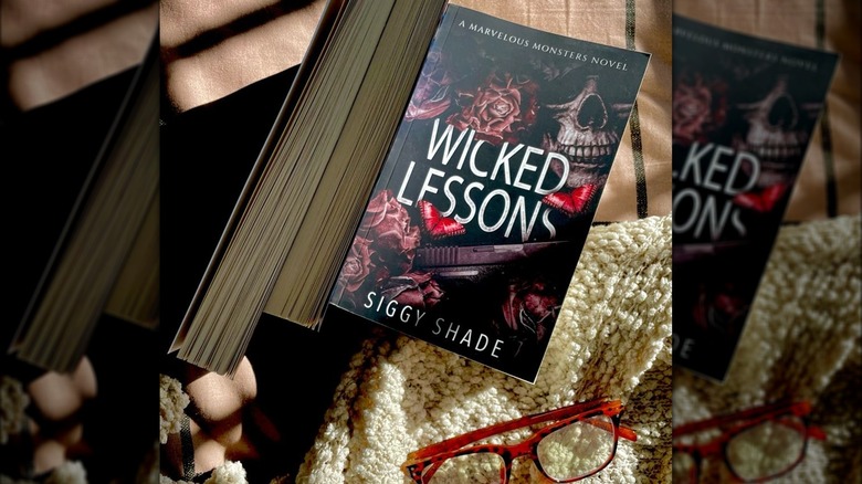 Libro Wicked Lessons e un paio di occhiali da lettura