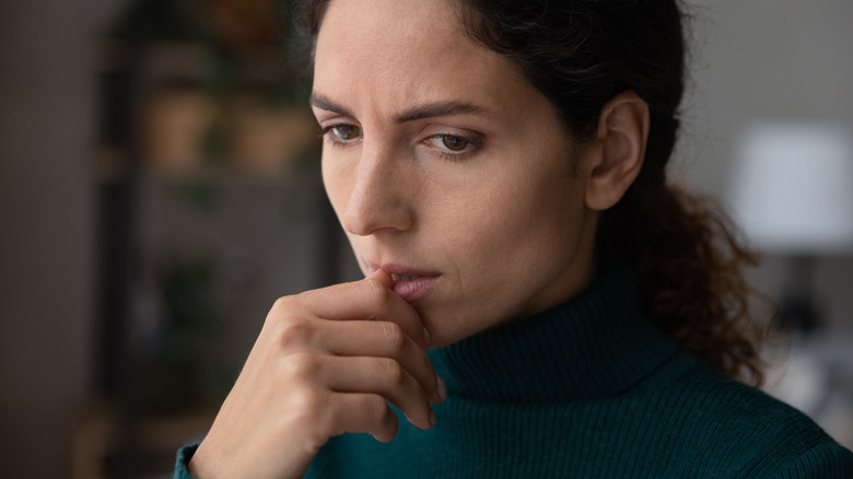 Donna che si mangia le unghie mentre pensa