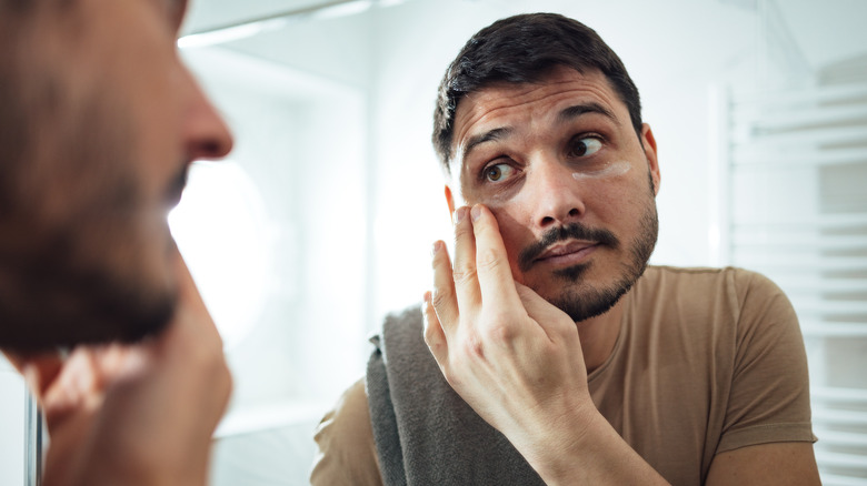 Uomo che applica la crema sotto gli occhi