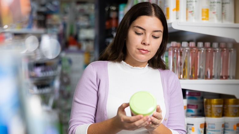 Donna che legge gli ingredienti per la cura della pelle