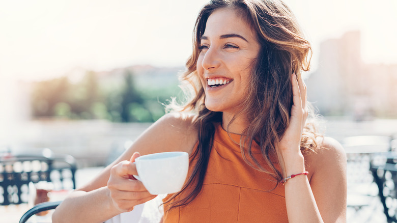 Donna sorridente che beve caffè fuori