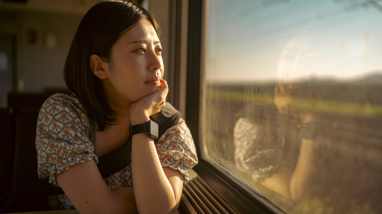 Donna pensierosa che guarda fuori dal finestrino del treno