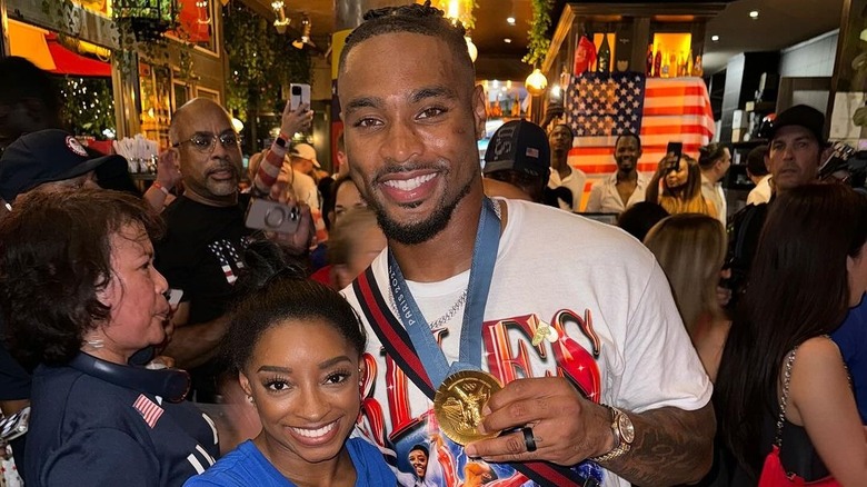 Simone Biles e Jonathan Owens indossano una maglietta bianca e una medaglia olimpica d'oro