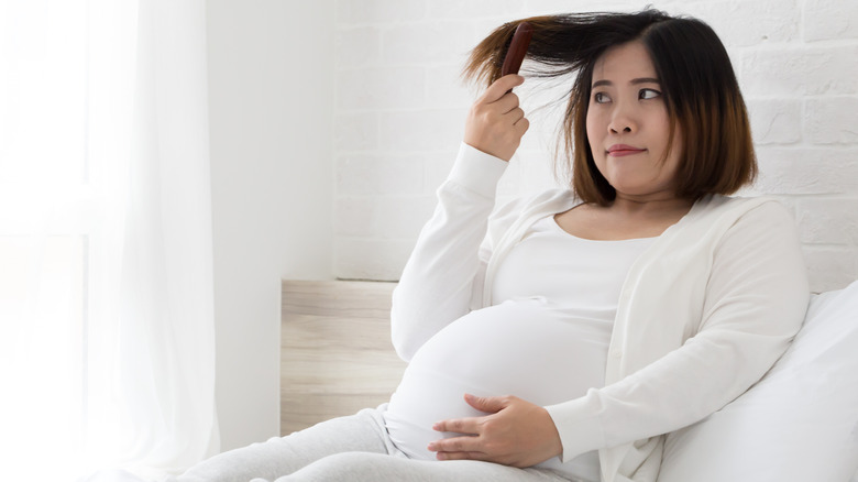 Donna incinta che spazzola i capelli sul letto