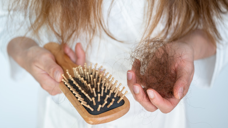 Mani di donna che puliscono i capelli dalla spazzola