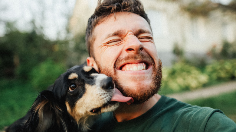 Uomo sorridente che si fa leccare dal cane