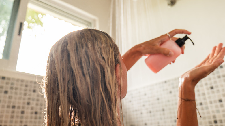 Donna che applica il balsamo sui capelli sotto la doccia