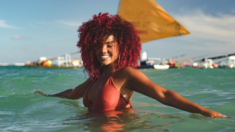 Donna con capelli color borgogna che nuota nell'oceano