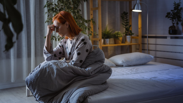 Donna stressata seduta sul letto da sola