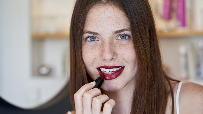 Donna che applica il rossetto rosso scuro